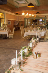 Wedding table decor full of rose and eustoma flowers, candles and peach colored fabric. Luxury rich restaurant interior. Indoor. Copy space