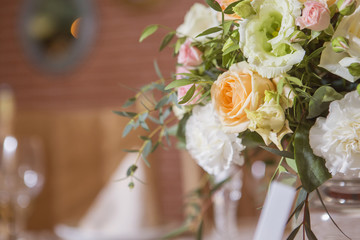 Wedding table decor full of rose and eustoma flowers, candles and peach colored fabric. Luxury rich restaurant interior. Indoor. Copy space