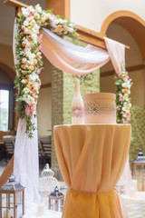 Wedding arch decor full of rose and eustoma flowers, candles and peach colored fabric. Luxury rich restaurant interior. Indoor. Copy space