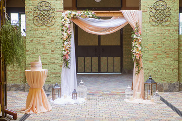 Wedding arch decor full of rose and eustoma flowers, candles and peach colored fabric. Luxury rich...