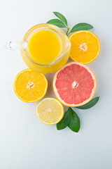 Fresh orange juice and citrus fruits lime lemon grapefruit in a jar blue background healthy concept flat lay