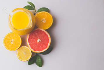 Fresh orange juice and citrus fruits lime lemon grapefruit in a jar grey background healthy concept flat lay