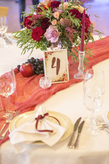 Set of wine flowers on a wedding table surrounded by plates, tablecloths and candles. Interior. Copy space