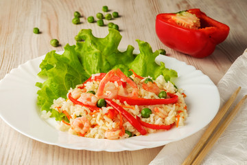 Boiled rice with vegetables and fried shrimp on a lettuce on white plate. A healthy and tasty dish of chinese cuisine.