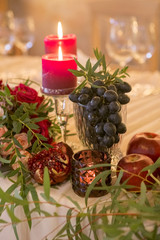 Set of wine color candles on a wedding table surrounded by light garland and flowers. Interior. Copy space