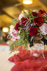 Wine color flowers on a wedding table surrounded by plates, tablecloths and candles. Interior. Copy space