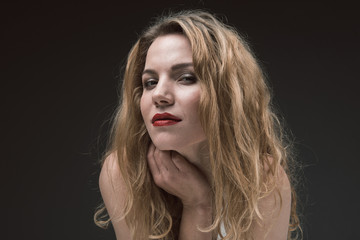 Fototapeta premium Portrait of attractive joyful woman with beautiful wavy hair looking at camera with mysterious smile. Isolated on background