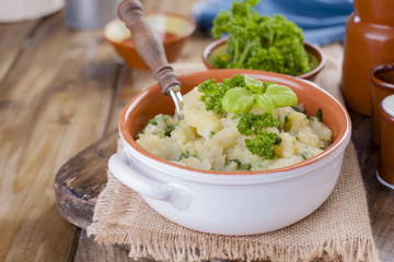 Mashed potatoes with basil and fresh parsley. Lunch in the style of a duck. Ceramic ware. Wooden background. Vegetarian food.