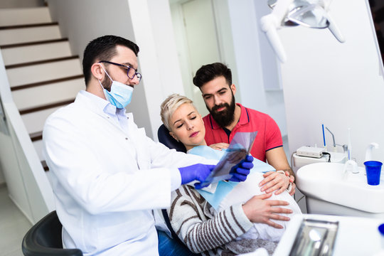 Attractive bearded man with his pregnant wife having medical treatment in dental office