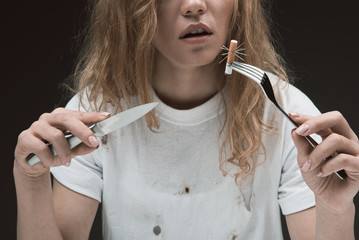 Peaceful woman holding knife and fork with prickly cigarette end on it. Isolated on background
