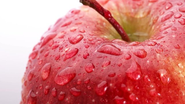 beautiful Red Apple with water drops rotates on white background, close-up