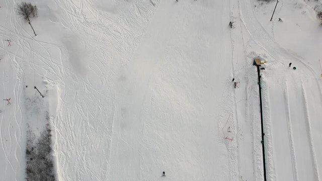 People descend on the ski slope. Winter snowy weather - aerial footage