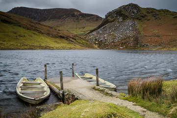 Two dilapidated boats moored at the jetty on Llyn y Dywarchen in the Snowdonia National Park, Wales.