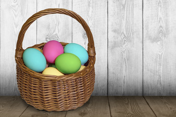 Easter basket filled with painted eggs over wooden table