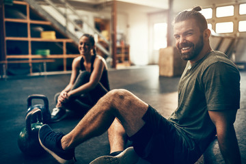 Smiling young people sitting in a gym after working out