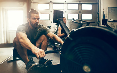 Fit man working out during a gym rowing machine class