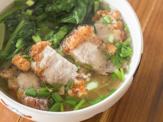 Clear water noodles with crispy pork on wooden table