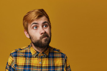 Portrait of young unshaved guy looks aside with bewilderment, facial expression. Isolated over...