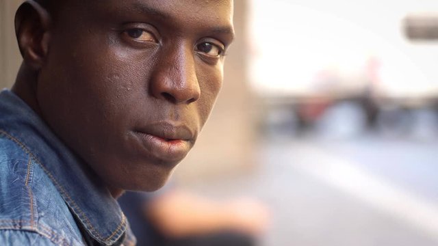 Young black man turning his head and looking sadly at camera