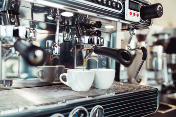 Espresso pouring from coffee machine into coffee cup.