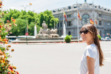 Young tourist woman in front Cibeles Fountain, one of the most famous monuments of architecture of Madrid located on the Cibeles square in the Centre of Madrid, Spain