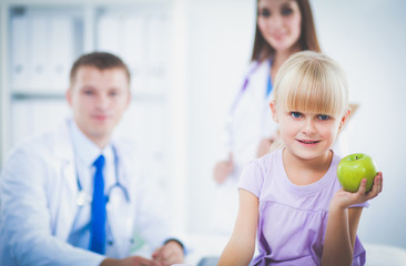 Obraz premium Child and medicine concept - female doctor giving an apple to little girl . Child and medicine concept