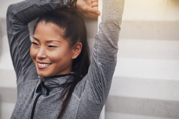 Sporty young Asian woman stretching outdoors before exercising