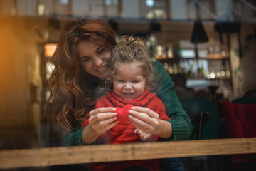 Fototapeta premium I give you my love. Glad woman is showing small toy heart to her little daughter. Girl is looking at it with admiration and smiling