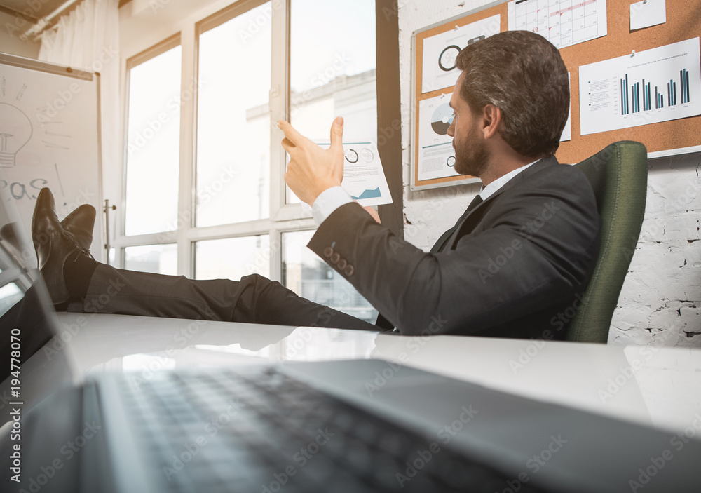 Poster searching for solution. side view of elegant bristled businessman is sitting in office while putting