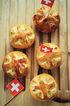 Celebrating Switzerland National Day on August 1st with traditional symbols like swiss flag red with white cross. Special bread buns with cross shape cut. Red berry sauce with  white cross.