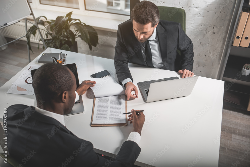 Poster another point of view. top view of two businessmen are sitting at table opposite. they are discussin