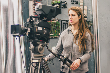 Obraz premium Behind the scene. Female cameraman shooting film scene with camera