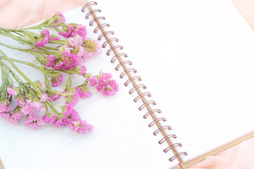 White open notebook and purple flower on pink fabric, soft focus with orange light vintage style