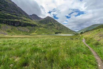 A trail in Glencoe valley with Loch Achtriochtan in the foreground, Highlands, Scotland, Britain