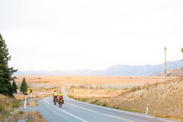 A couple of travelling cycling on the way traveling around in South Island, New Zealand