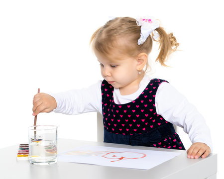 A little girl is drawing at the table.