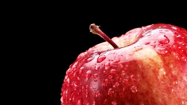 beautiful Red Apple with water drops rotates on black background, close-up