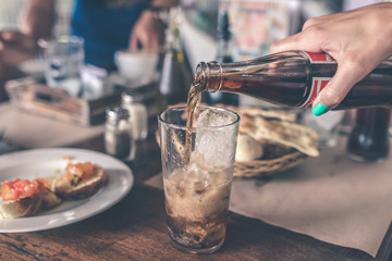 Pouring Cola with ice cubes. Cola drink with Ice and bubbles. Water drops on glass. Soda closeup. Restaurant.