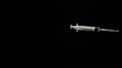 Medical syringe falling on black background, Ultra Slow Motion - Powered by Adobe