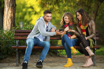 Three young people on a bench talking