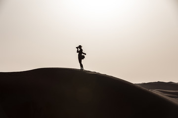 Young tourist in shorts hiking in giant dunes.