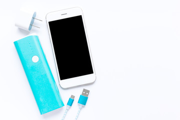white smartphone with battery bank and usb charging cables in top view