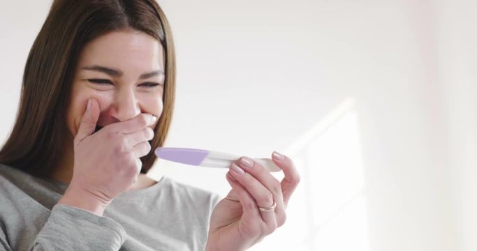 A beautiful woman takes a pregnancy test and as soon as she reads that she is pregnant, she explodes in a moment of happiness and joy for the future birth of her child. Concept of: birth, life, family