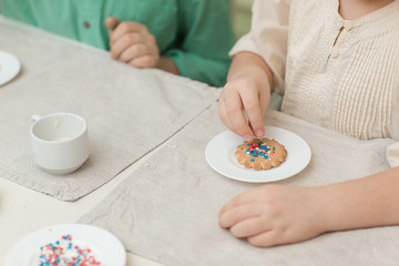 Obraz na płótnie Canvas Cute children decorate cookies at a table in the home kitchen