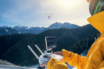 remote controlling a flying drone on winter mountain top