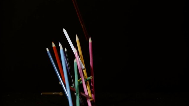 Colorful pencils falling on a black surface, Ultra Slow Motion 