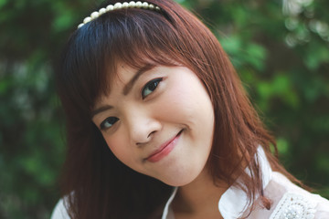 Close up of young pretty Asian woman in white dress with garden background.