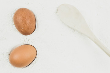 Whole egg and wooden spoon on flour background. Preparation of baking, kneading dough. Homemade food.