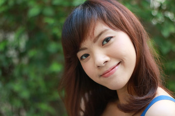 Close up of young pretty Asian woman in blue dress with garden background.