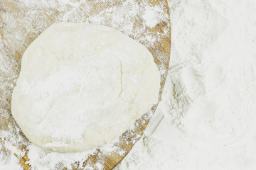 Piece of dough on white flour as background